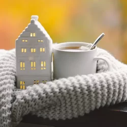 Casita, tacita de café y bufanda blanca del blog de cómo adaptar tu hogar y reducir el consumo energético en invierno