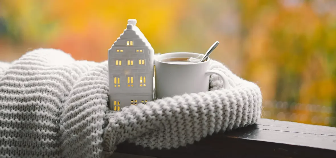 Casita, tacita de café y bufanda blanca del blog de cómo adaptar tu hogar y reducir el consumo energético en invierno